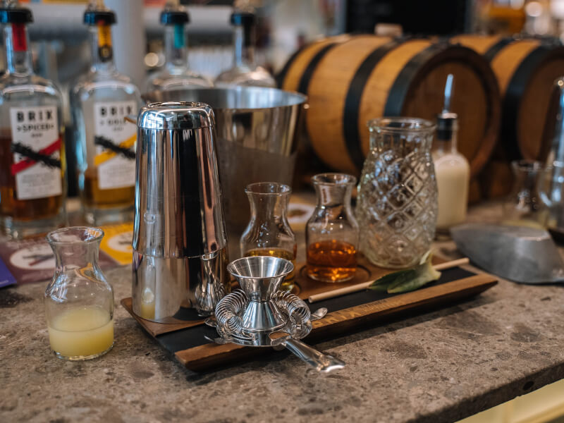 A table top full of supplies for a cocktail making class including, measured ingredients and a shaker.